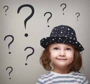 Happy thinking kid girl in hat looking up on questions